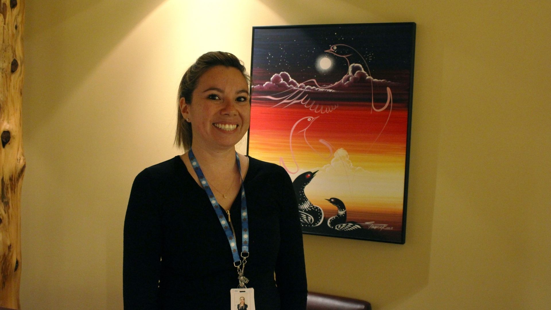 Photo of Alyshia in front of Indigenous painting
